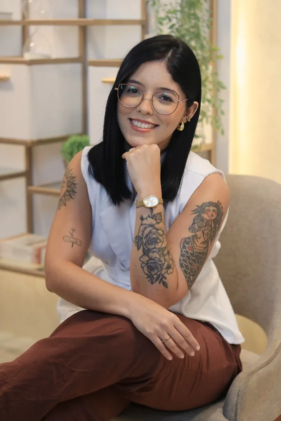 Andressa Meneses sentada e sorrindo, em retrato profissional acolhedor