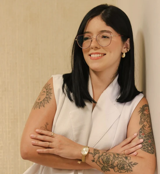 Andressa Meneses apoiada em uma parede, sorrindo, em retrato profissional